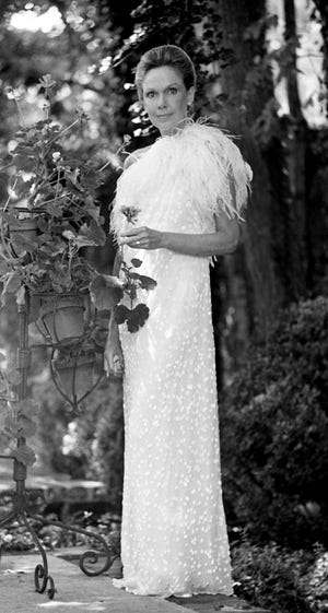 Clare Armistead shows off a dress, a slim white column topped with marabou feathers by Pauline Trigere, at her home on June 3, 1982. Armistead planned to wear it to the Swan Ball.