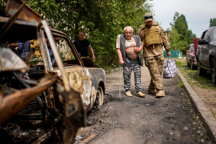 A volunteer helps a man leaving his home May 31 after the building he lived in was damaged by an overnight missile strike in Sloviansk, Ukraine.