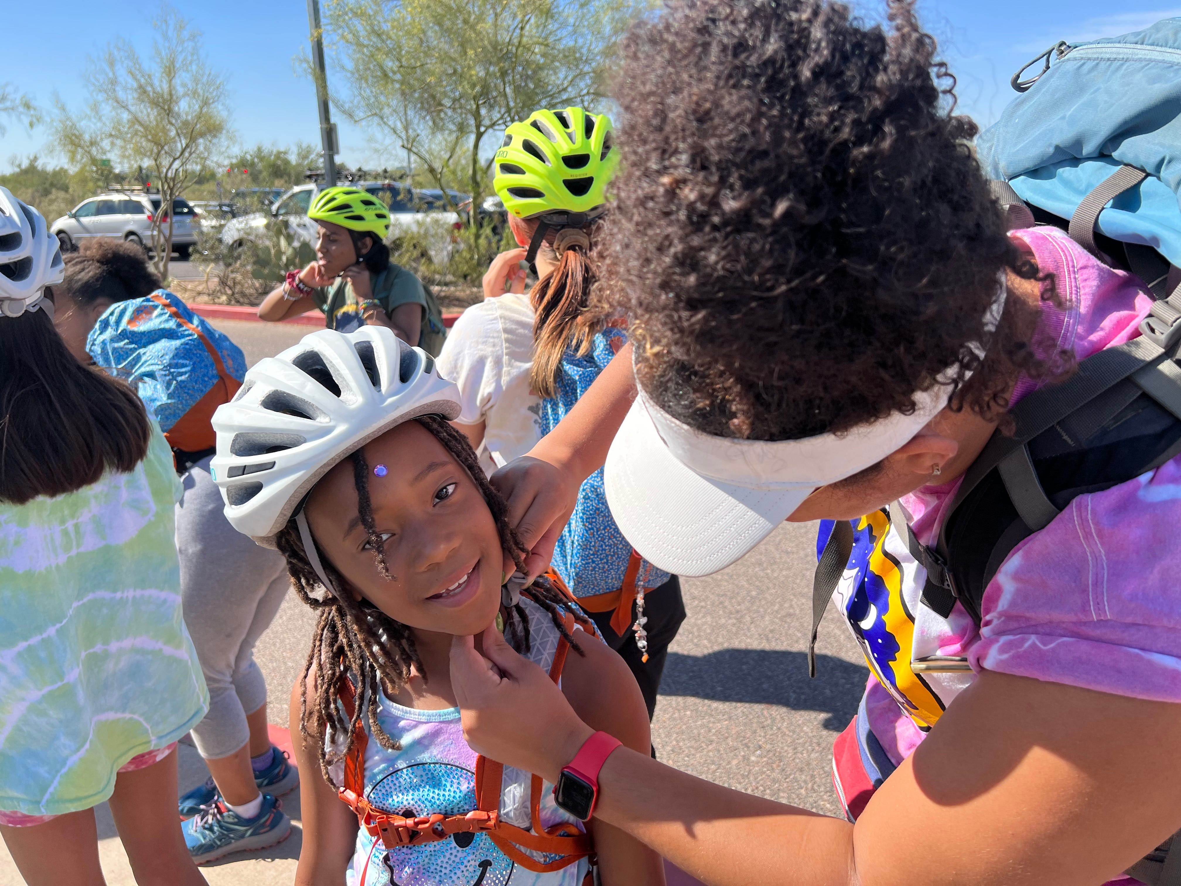 Atabey Member Samir Clinton gets fitted for her mountain biking helmet by volunteer Quin Works at Papago Park.