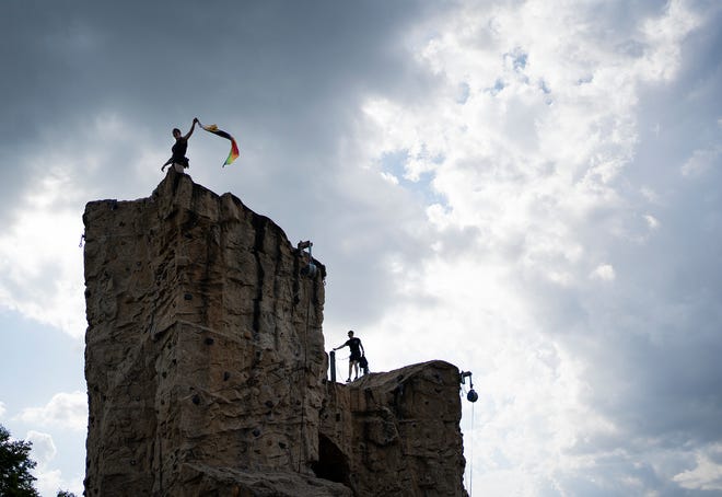 Caroline Thompson waves the LGBTQ+ flag at the top of the Audubon Climbing Wall during an event hosted by the new nonprofit for LGBTQ+ rock climbers, Queer Climbing Columbus. The group is hosting multiple events for Pride Month.