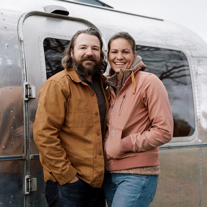 Adam Kendall and Kate Leese smile in front of their airstream.