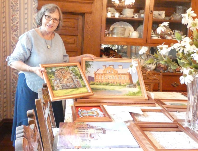 Peg Vasil displays works created by local artists for a special project showcasing Bucyrus history.  The paintings will be part of an exhibit during this month's First Friday event downtown.