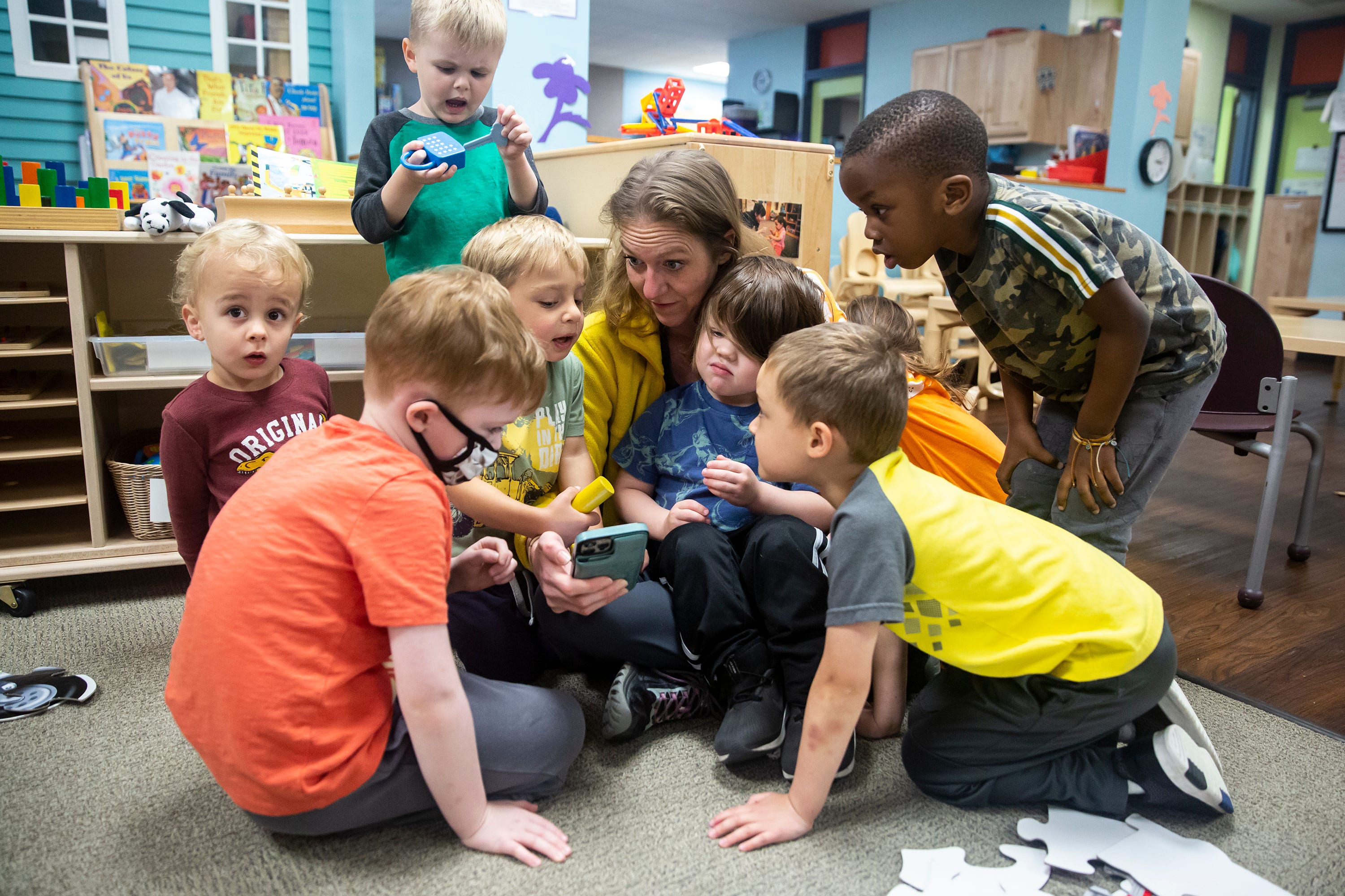 Sadie Gunther, a Child development specialist, shows a group of kids photos of animals on her phone, at the DMACC Child Development Center, on May 24, 2022, in Ankeny. The child development center is a lab school providing training for early childhood education teachers.