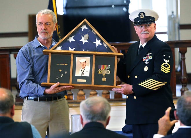 Martin Riordan, left, representing his brothers and sisters holds a shadow box honoring his late brother George with Navy Command Master Chief Bruce Lee during a Bronze Star ceremony at Dover City Hall Friday, June 3, 2022.