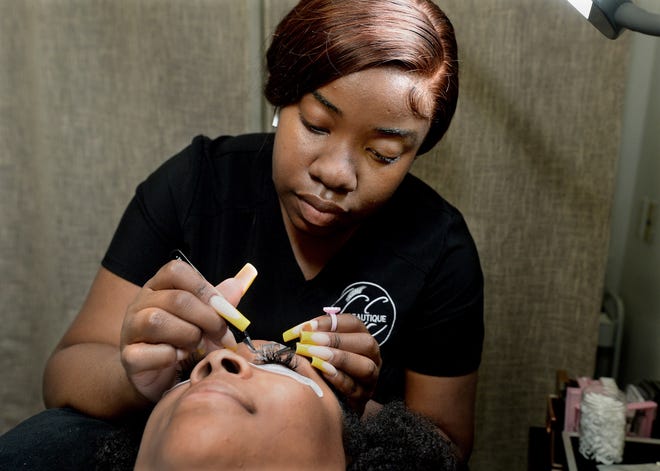Genesis Bennett, back, adds false eyelashes to customer Keneisha Boozer's own lashes at the GeBeautique in Springfield Thursday June 2, 2022. [Thomas J. Turney/ The State Journal-Register]