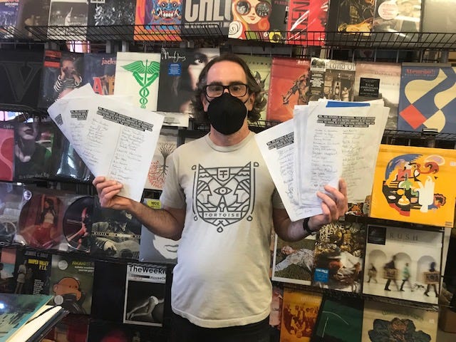 Andrew Schaer, propietario de Hear Again Records en el centro de Gainesville, muestra un puñado de peticiones firmadas por residentes que se oponen a que la ciudad restablezca el estacionamiento medido en las vacantes del centro.