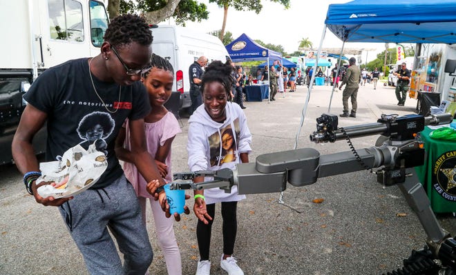 Devin Allen 14, catches the cup dropped by the robot. His cousins Jada Battle, 9, and SaraeÕa Mann, 11, react with him. The robot was on display as part of the Lee County Sheriff's booth. The 15th Annual Dunbar Neighborhood Watch "Unity in the Community" celebration was held on High Street in Fort Myers, Thursday, June 2, 2022. Ms. Taunya put on the celebration to celebrate the last day of school. Every year she welcomes hundreds of kids for the free event. Waterslides, free food, music and so much more. The Fort Myers Police Department, Lee County Sheriff, Lee Health and other vendors were on hand. 