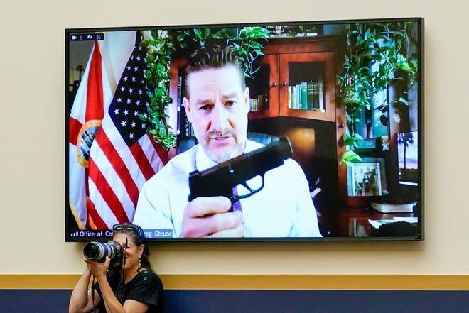 Rep. Greg Steube, R-Fla., holds up his handgun as he speaks via videoconference from his home at a House Judiciary Committee meeting on a series of Democratic gun control measures called the Protecting Our Kids Act.