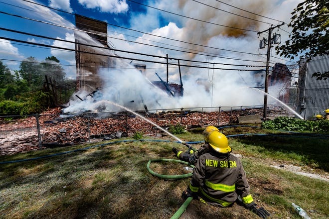 Firefighters pour water on the remnants of a collapsed mill in Orange during a massive fire there Saturday.