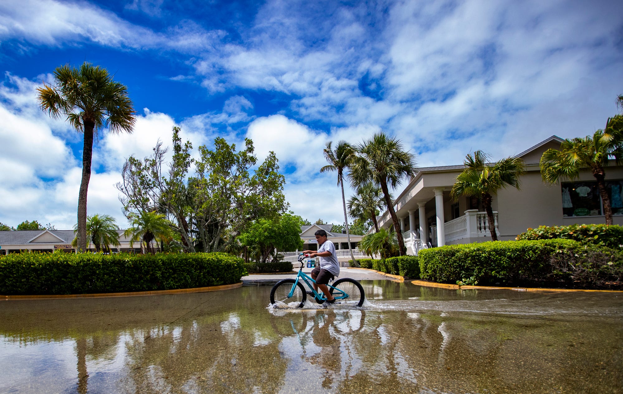 A bicyclist splashes along a flooded parking lot in Florida on Saturday, June 4, 2022.