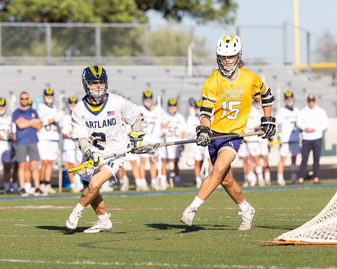 Hartland's Bo Lockwood looks to come out from behind the net while defended by Grand Ledge's Bradley McDiarmid during a state Division 1 lacrosse quarterfinal Friday, June 3, 2022 at Parker Middle School.
