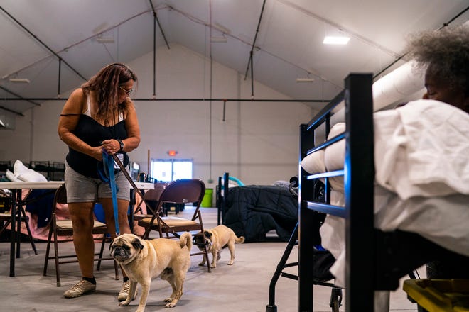 Ann Paskwietz brings her dogs inside the Respiro structure at Central Arizona Shelter Services on Saturday, June 4, 2022, in Phoenix. The structure offers unhoused residents an enclosed air-conditioned area with a hundred beds.