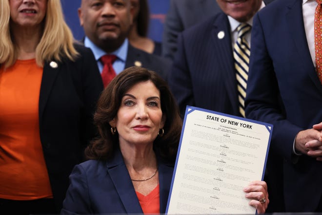 Gov. Kathy Hochul holds up signed legislation as she is surrounded by lawmakers during a bill signing ceremony at the Northeast Bronx YMCA on June 06, 2022 in New York City.