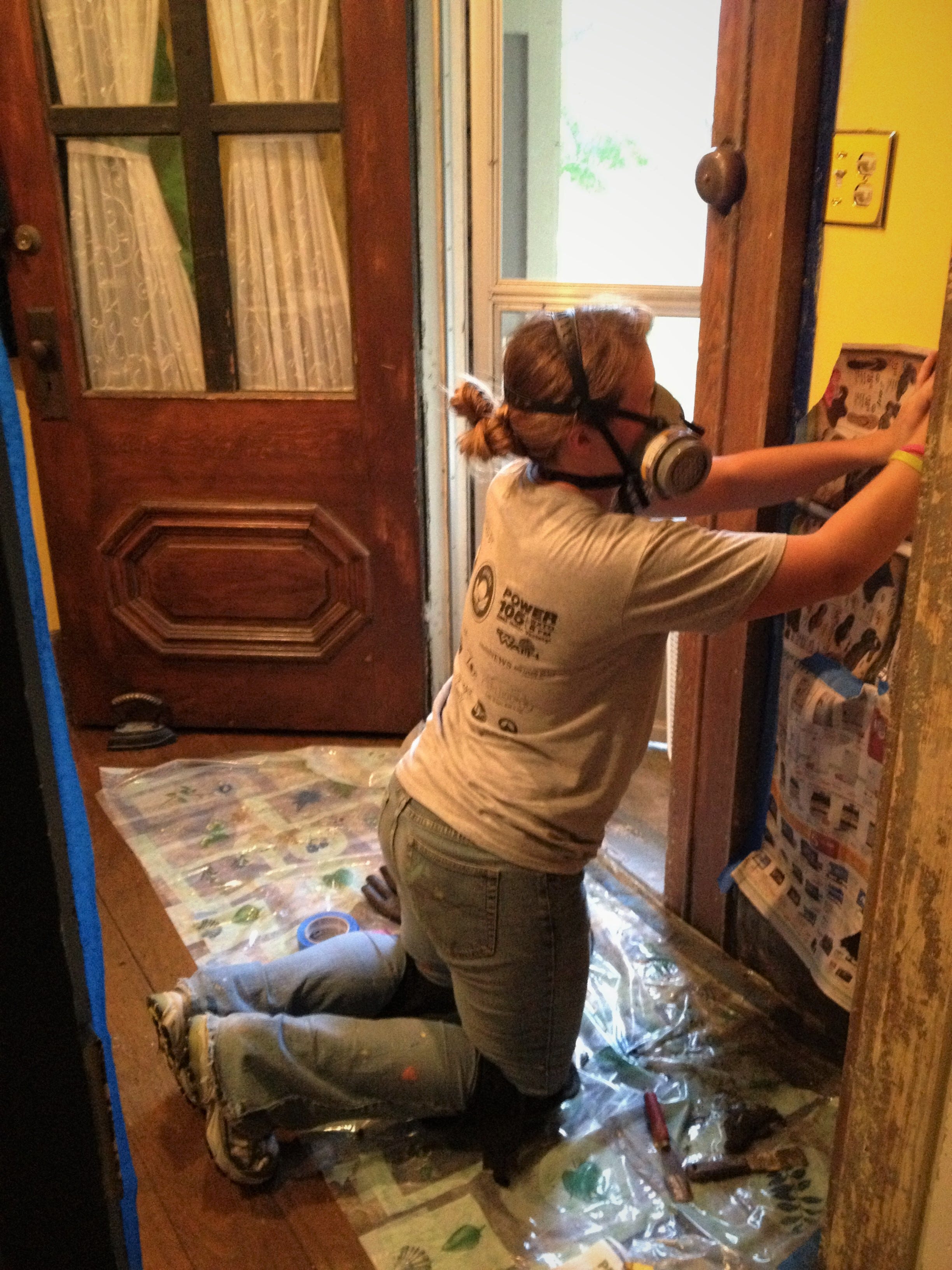 In 2013, daughter No.  2 picks up where daughter No.  3 left off as they tag-teamed the process of stripping paint from woodwork in the front hallway of our old house.  The front door, with its crude, four-pane replacement for the original window glass, is visible in the background.