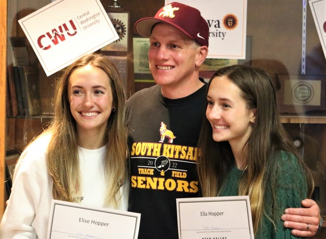South Kitsap girls track and field coach Paul Zimmer stands with Elise Hopper (left) and twin sister Ella Hopper (right) during a ceremony honoring college-bound athletes Tuesday at South Kitsap High School. Elise Hopper is headed to Central Washington University, while Ella Hopper will attend Utah Valley University.