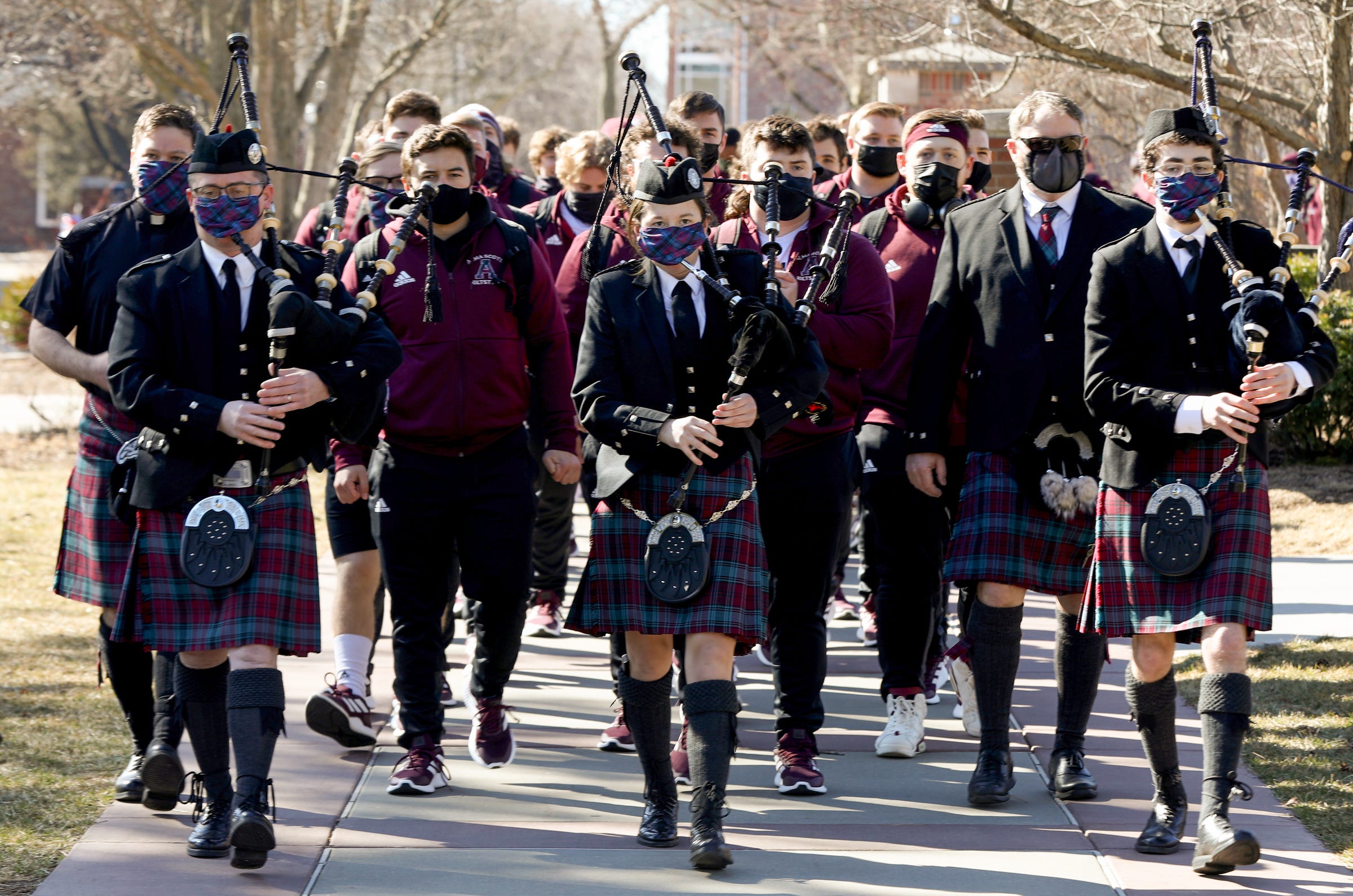 In an Alma College tradition, Alma College head football coach Jason Couch and his team follow bagpipers through campus on their way to the football field where they would play Adrian College on campus in Alma, Michigan on Saturday, March 20, 2021.