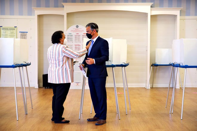 Assemblymember Mia Bonta, left, places an "I voted" sticker on her husband, Attorney General Rob Bonta's, jacket after completing their ballots at the South Shore voting precinct on Tuesday, June 7, 2022, in Alameda, Calif.