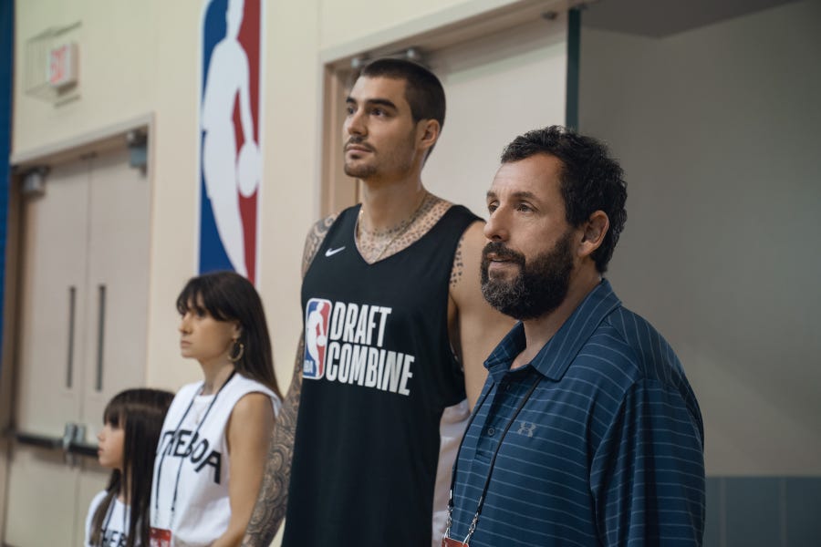 Juancho Hernangomez (center) stars as NBA prospect Bo Cruz and Adam Sandler is pro scout Stanley Sugerman in Netflix's "Hustle."