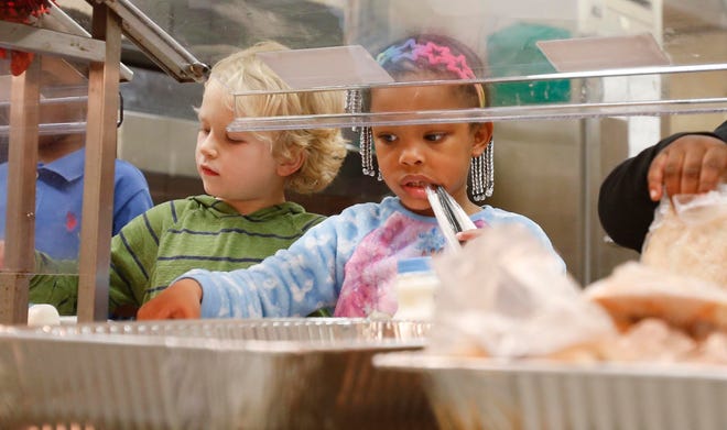 Tuscaloosa city and county schools will offer free summer meals into July. In this 2018 file photo, Diilyn Bishop, 4, and Carter Lockhart, 5, in green, move through the meal line in the cafeteria at Woodland Forrest Elementary. [Staff file photo]
