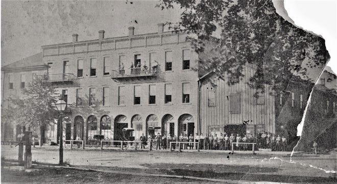 Workers and carriages stand in front of the Ochs Carriage factory on West State Street, Fremont, in this fragile early photograph before paving, trolley tracks, and overhead wires. The original building in the center, probably dating back to the 1860s, still stands between Park Avenue and Grace Lutheran Church, though the building at the right is now gone. Notice the street lamp and old pump in the foreground at the left. (Submitted by Larry Michaels and Krista Michaels)
