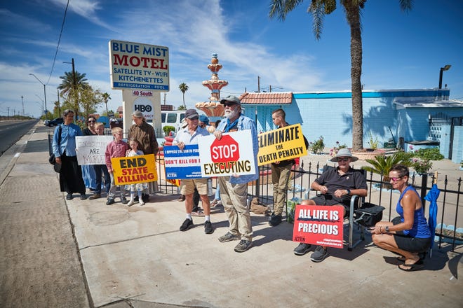 People hold signs and protest the death penalty across the street from the Arizona State Prison ahead of the execution of Frank Atwood on June 8, 2022.