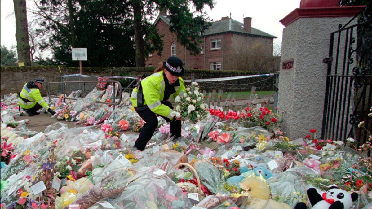 A police officer arranges bouquets of flowers in rows at a side entrance to Dunblane Primary School in Dunblane, Scotland on March 15, 1996.