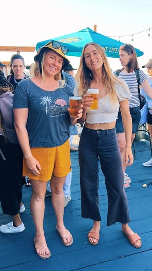Surf photographer Sara Lee (left) and professional surfer Anna Gudauskas enjoy a few cold Kona beers after cleaning up the beach at Rockaway Beach in New York.