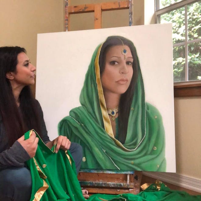 Shabana Kauser stands next to one of her paintings.