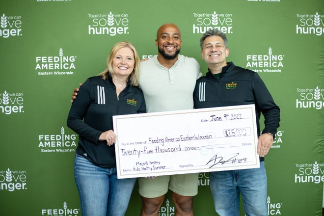 AJ Dillon with Feeding America Eastern Wisconsin's Patti Habeck and Scott Marshall