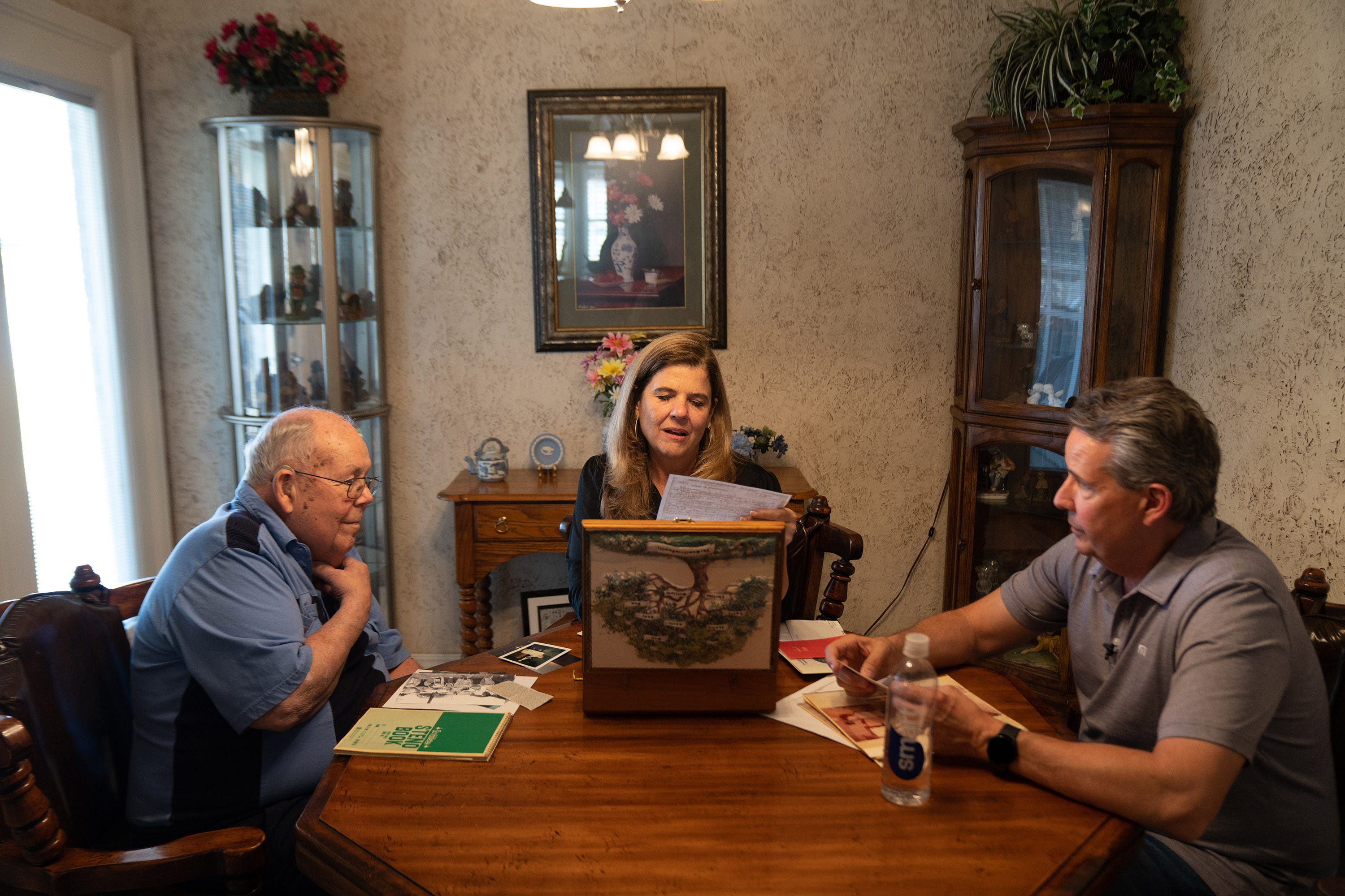 Nicole Carroll looks through a box of family letters and pictures with her uncle Larry Hamilton, left, and her brother, Chris Carroll, at her uncle's home in Amarillo, Texas, in May.