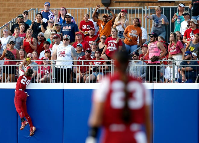 Oklahoma's Jayda Coleman (24) leaps over the wall to make a catch in the first inning during Game 2 of the Women's College World Series Championship Series between the University of Oklahoma Sooners (OU) and the Texas Longhorns at the USA Softball Hall of Fame.  Stadium in Oklahoma City, Thursday, June 9, 2022. 