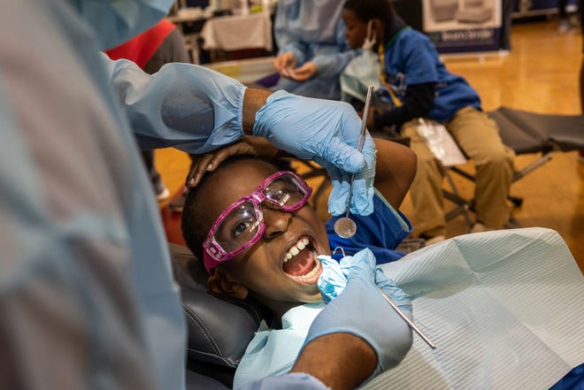 Brenda Scott Academy student Jordan Mchee sits in a chair as Lansing Community College Dental Hygiene student Jaymar Benton cleans his teeth, during an event at Brenda Scott Academy in Detroit on Friday, June 10, 2022. Detroit District Dental Society joined the Detroit Lions and Team Smile as volunteer dentists and dental staff to provide free dental care to students.