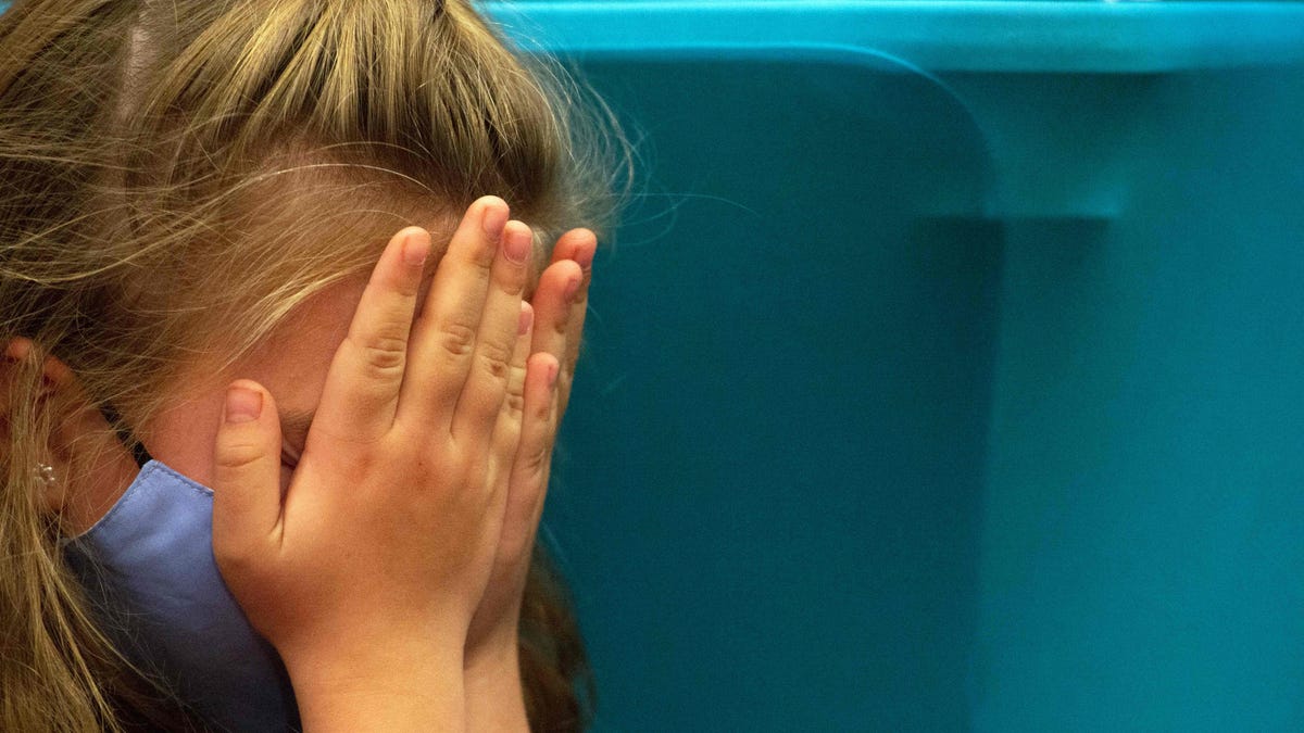 A child covers her face as she waits for her turn to receive the vaccine in Hartford, Connecticut, on November 2, 2021.