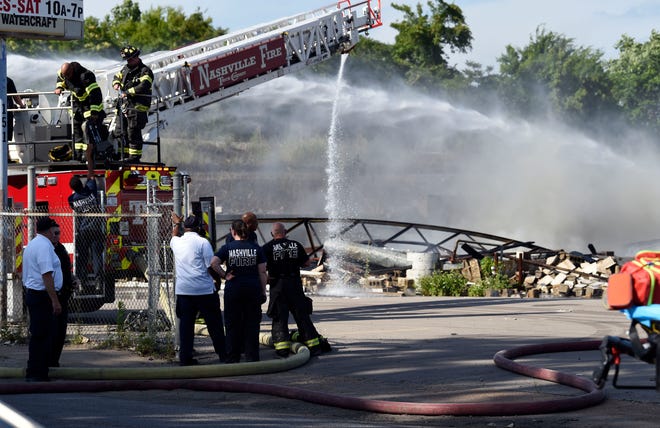 Nashville firefighters extinguish a warehouse fire along the 100 block of North 1st Street near Nissan Stadium during CMA Fest on Saturday, June 11, 2022 in Nashville, Tennessee.