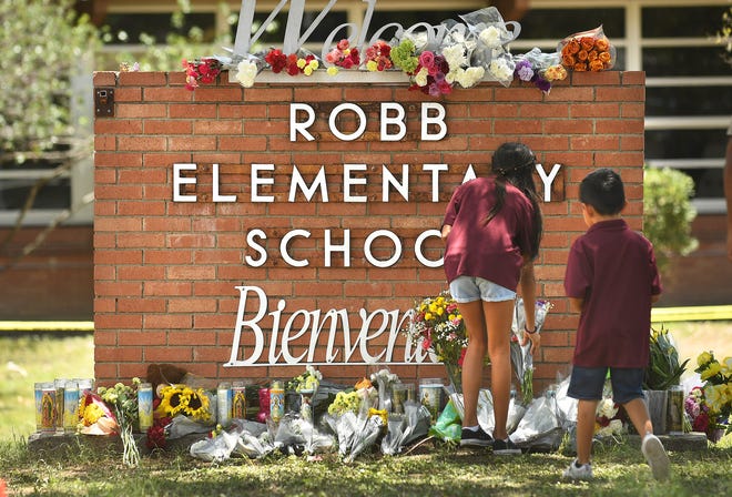 Family members who lost a sibling place flowers outside Robb Elementary School in Uvalde, Texas last month.