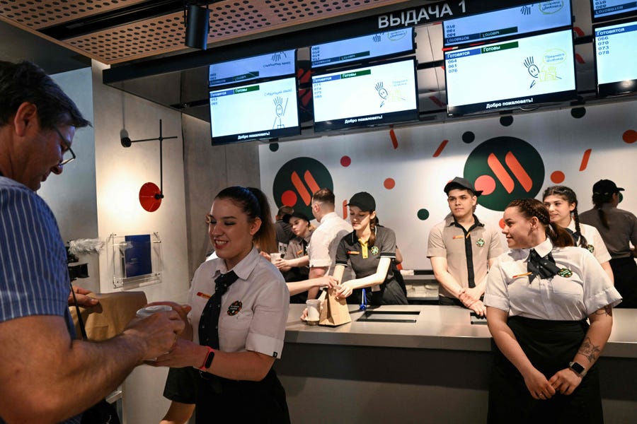 An employee gives a customer his food order in the Russian version of a former McDonald's restaurant after the opening ceremony in Moscow on June 12, 2022. Former McDonald's restaurants in Russia have been renamed "Vkusno i tochka" ("Delicious. Full Stop"), the new owner said ahead of their grand re-opening .