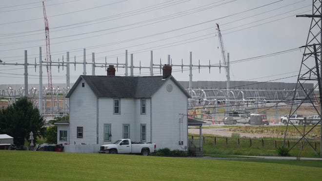 A farmhouse sits across Parsons Avenue from the construction of the Google data center, seemingly surrounded by electric lines and an electric substation.