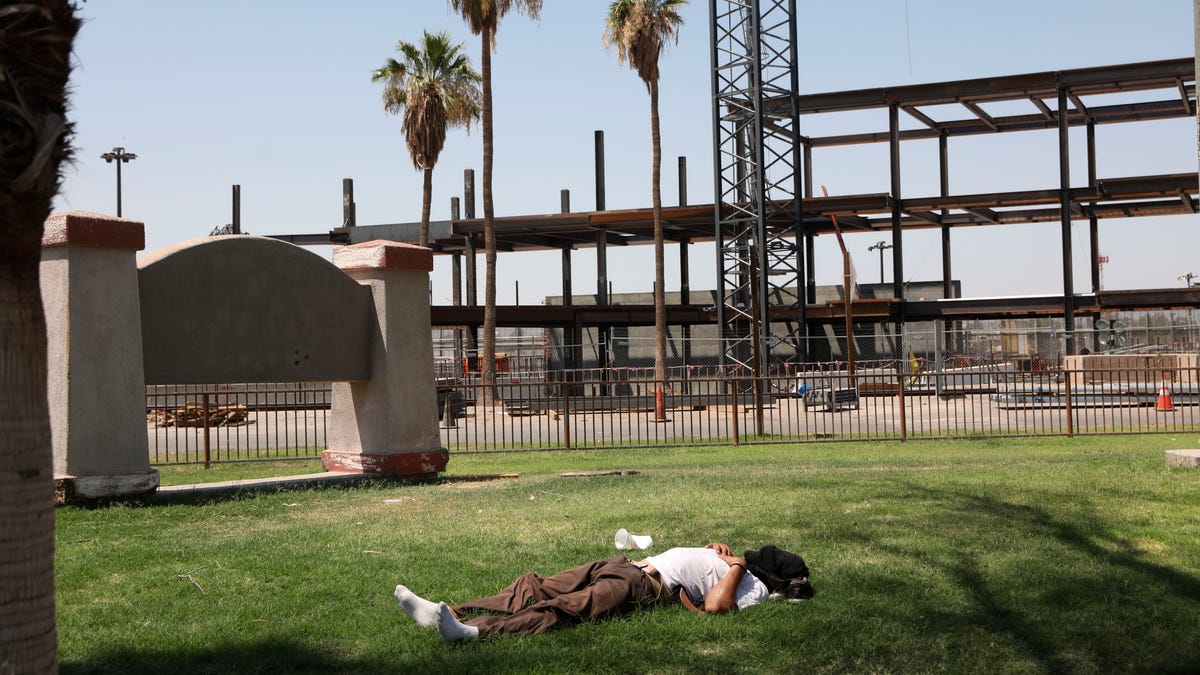 A man lies on the grass as the temperature reaches 115 degrees on June 12, 2022 in Calexico, California.