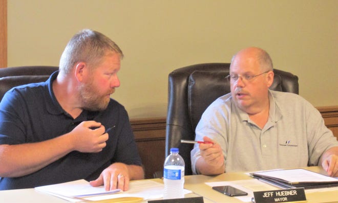 Village Administrator Nate Troyer (left) and Mayor Jeff Huebner talk about options for waterline and storm sewer projects in Millersburg during Monday's council meeting.