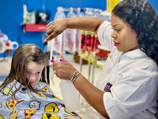Master Stylist NaTasha Middleton-Tucker sprays a client's hair at her Wiggidy Wacky Haircuts for Kids salon in Colonial Heights, Va.