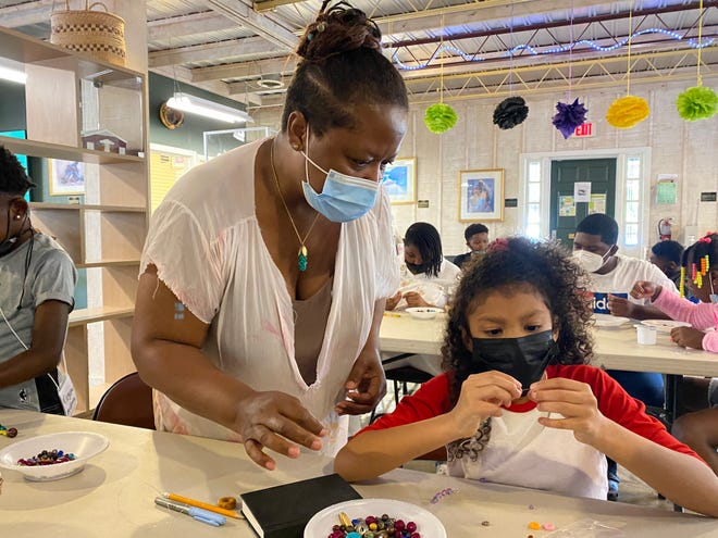 Odessa Lovett z U.Gotta Lovett pomaga Loyli Roseman podczas lekcji robienia biżuterii na obozie letnim w Afroamerykańskim Centrum Informacji i Zasobów Zdrowia w szpitalu St. Joseph's Candler.