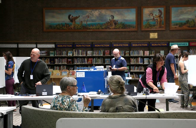 Election observers, sitting in middle, talk as people vote during the primary election at the Downtown Reno Library on June 14, 2022.