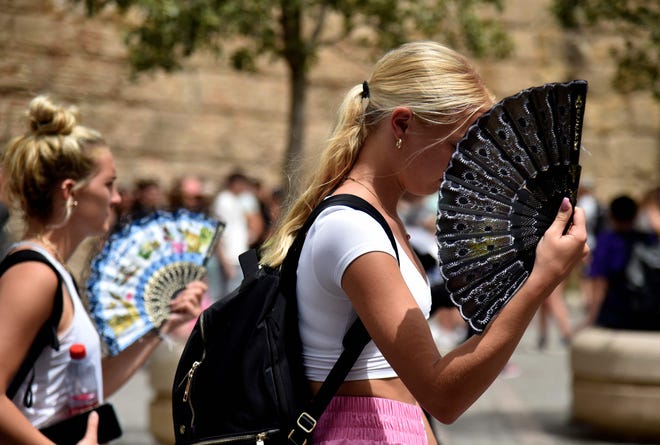Two women use fans to battle the scorching heat during a heatwave in Seville on June 13, 2022. The city recently suffered the world's first named heatwave.
