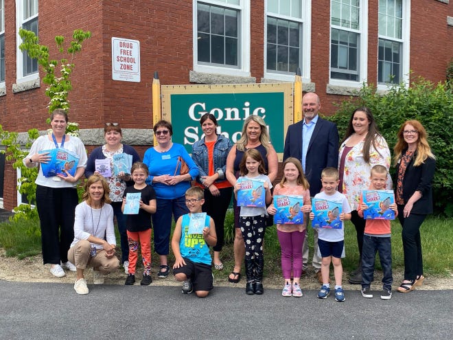 Students, staff members and representatives of Holy Rosary Credit Union (HRCU) and the Rochester Rotary Club stand with summer reading books outside the Gonic School. The books were donated by HRCU and the Rochester Rotary Club.
