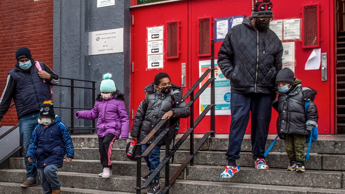 Children and their guardians wearing masks because of the pandemic, leave P.S. 64 in the East Village neighborhood of Manhattan, Dec. 21, 2021, in New York.