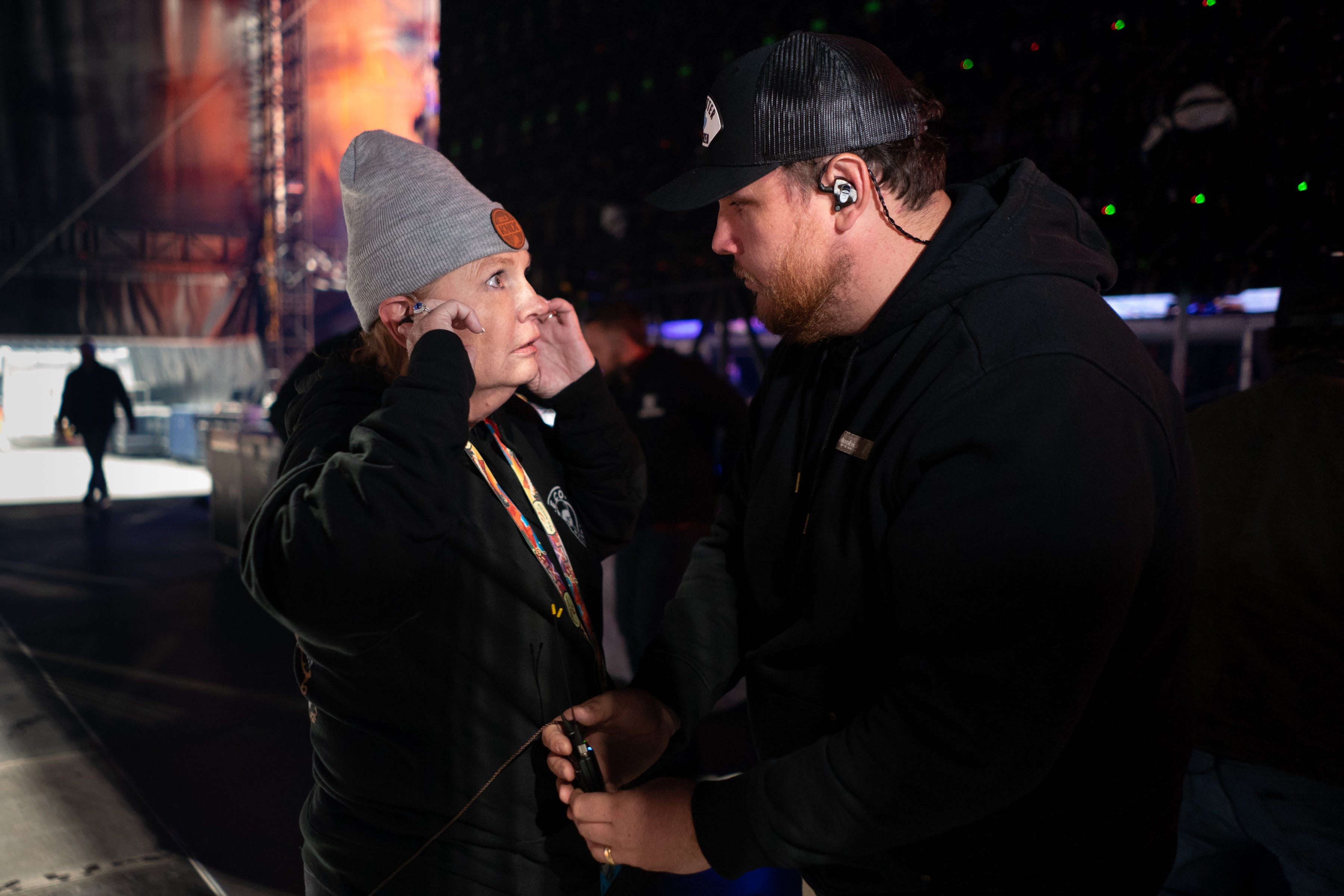 Luke Combs helps his mother, Rhonda Combs, set up her in-ear monitors before he performs at Empower Field at Mile High in Denver, Colo., Saturday, May 21, 2022. The show kicked off Combs’ first-ever headlining stadium tour.