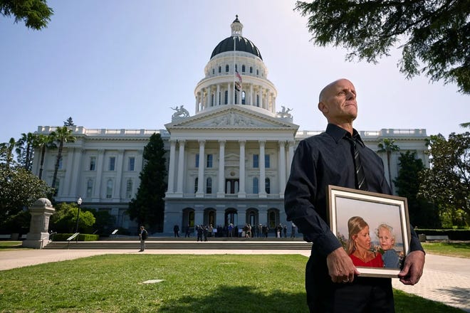 Doug Forbes poses for a portrait in front of the Capitol while holding a picture of his daughter Roxie, who drowned at a day camp in Pasadena a few years ago, and his wife, Elena Matyas, who passed away recently.