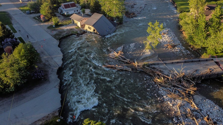 June 15, 2022:  A house sits in Rock Creek after floodwaters washed away a road and a bridge in Red Lodge, Mont.