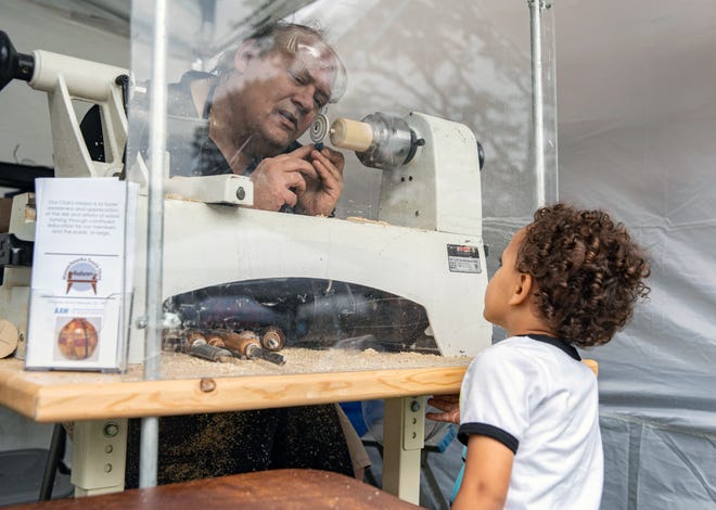 John Shooshan painting blue stripes on a gyro for Trista Reyes Erler, 4, of Cohasset, during the South Shore Art Festival at Cohasset on Friday, June 17, 2022