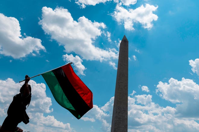 Marah O'Neal, waves an Pan-African flag as she attends a small anti-apartheid rally in the United States next to the Washington Monument in Washington, DC, on July 4, 2020.